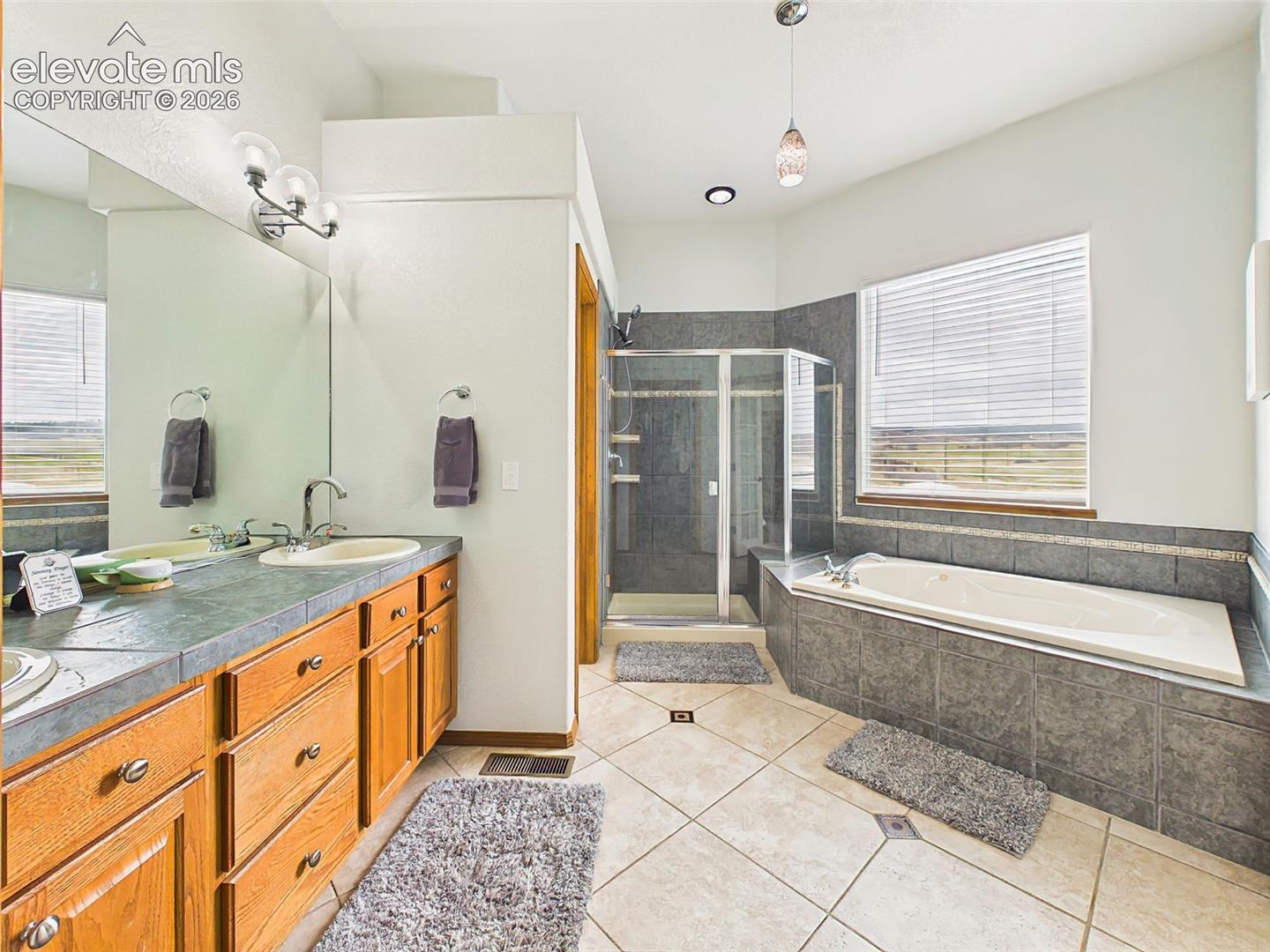 Generously sized primary bathroom with tile flooring, expansive vanity space, and a relaxing soaking tub retreat.