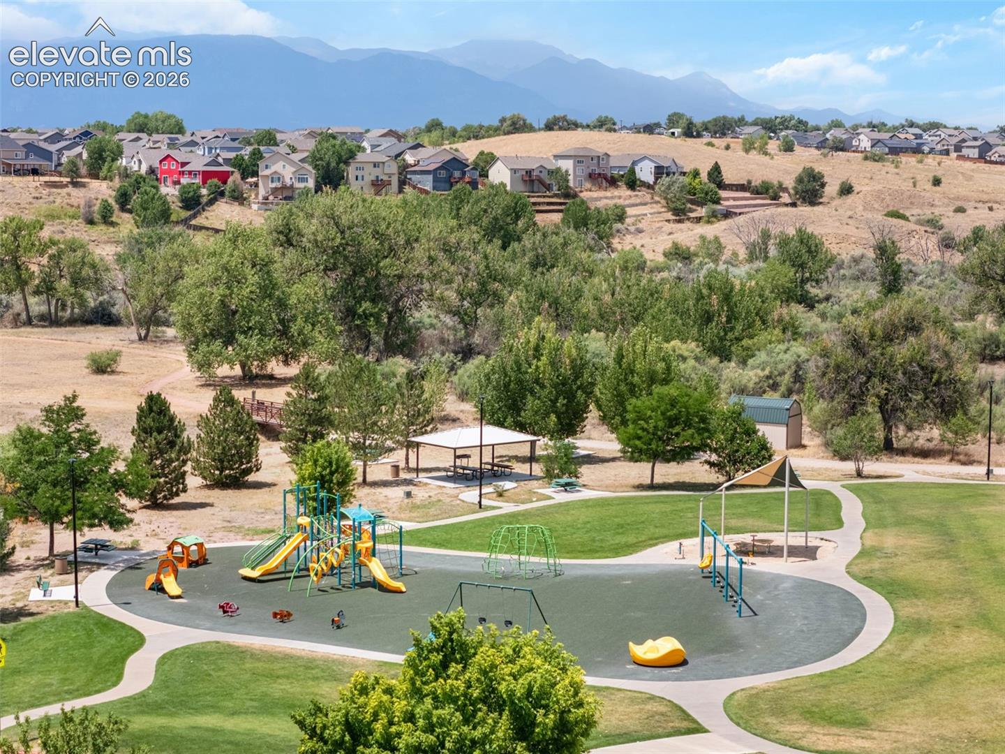 Community park featuring a playground with slides and swings, a covered picnic area, and walking paths