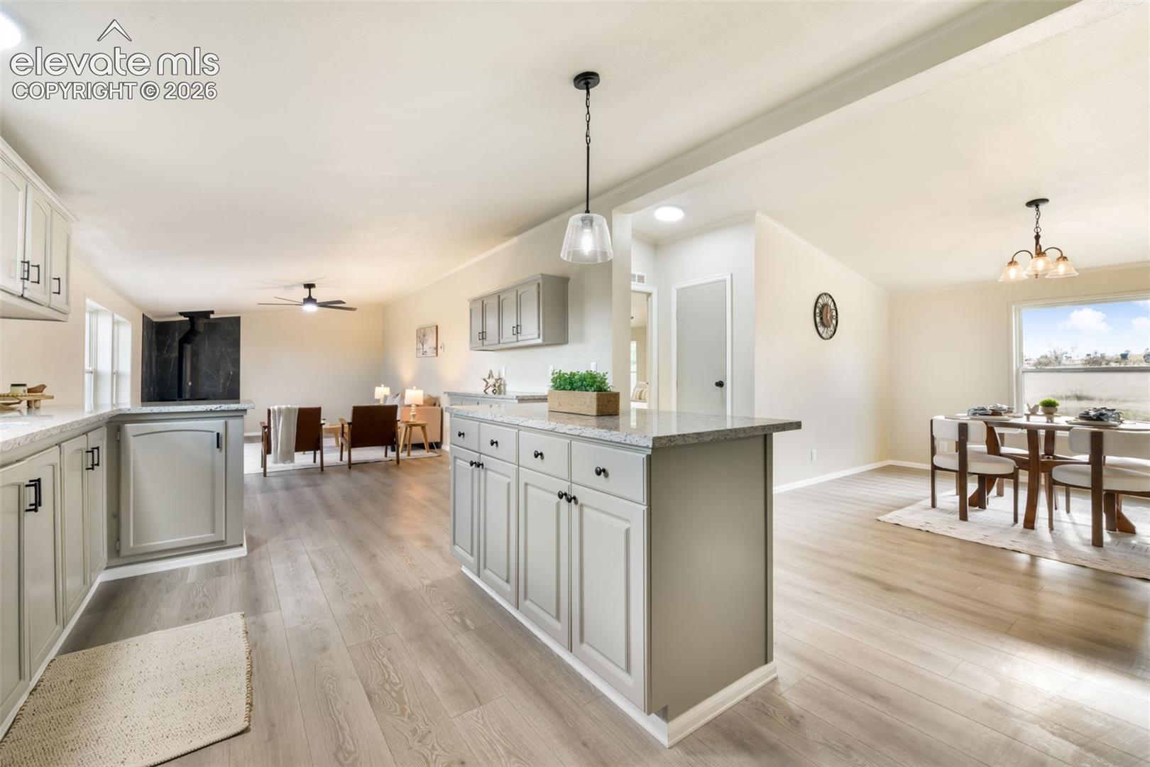 Light wood-finish flooring throughout, complemented by a kitchen island with storage and a stone countertop
