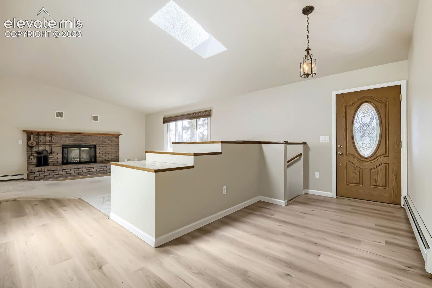 Entryway with wood-finish flooring, a decorative glass-insert entry door, and an overhead lantern-style pendant light