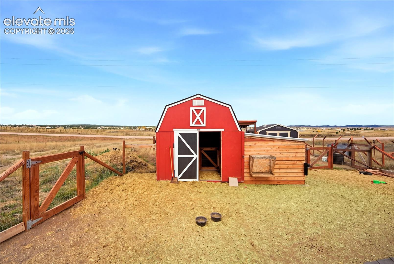 Red barn-style structure with wood siding, integrated wooden fencing, and natural terrain surroundings
