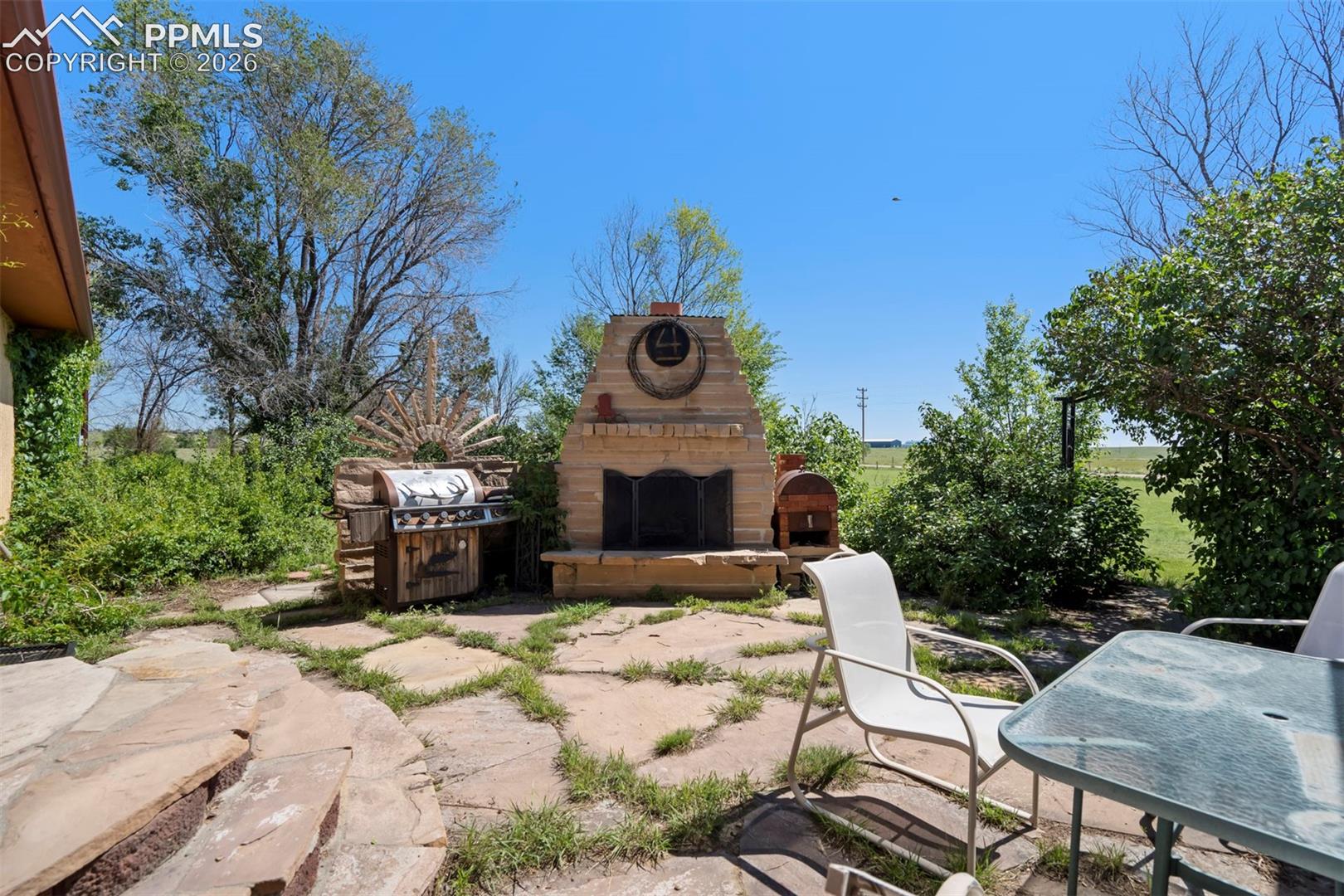 Stone patio featuring a built-in outdoor fireplace and an integrated grilling station