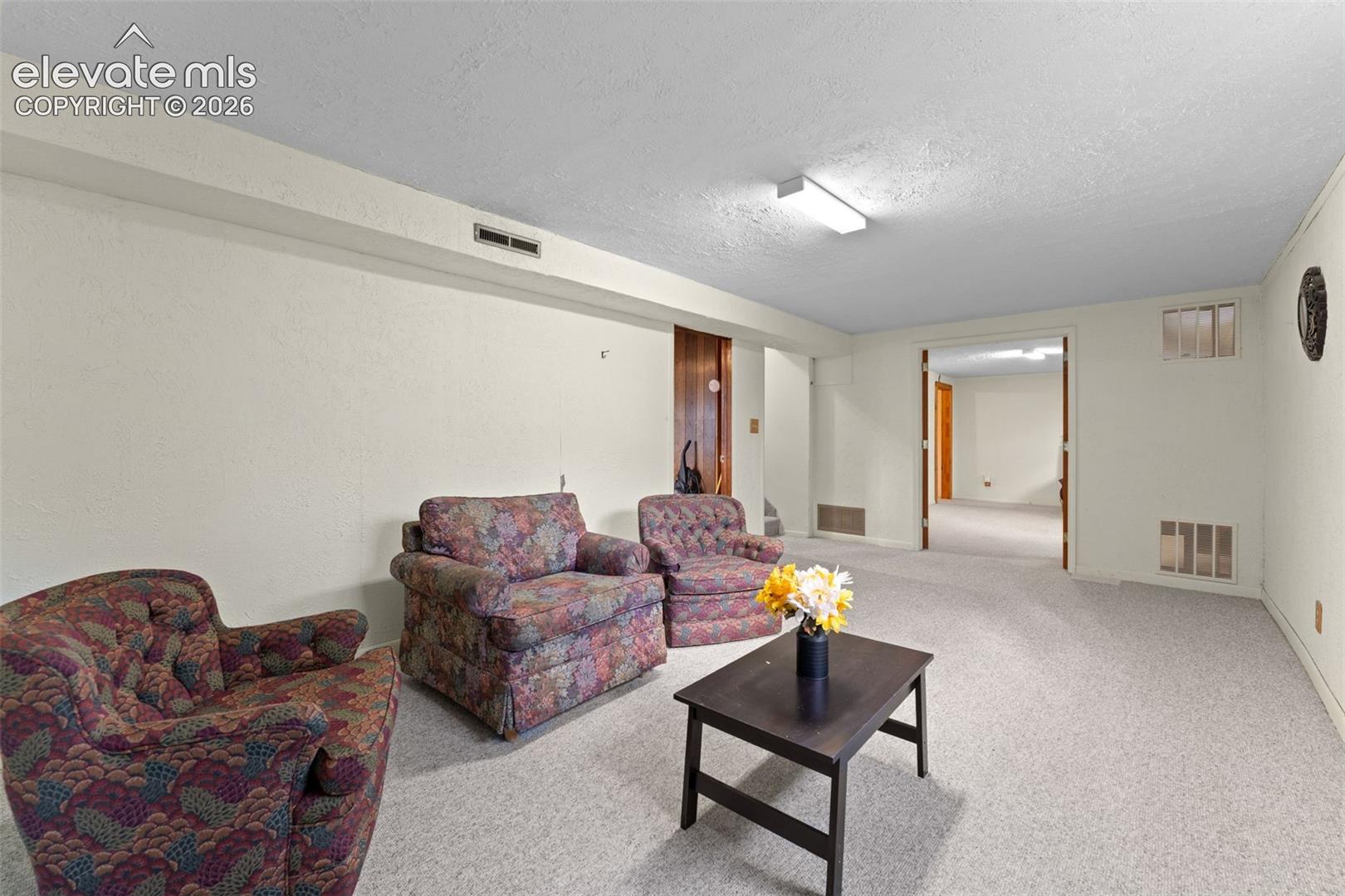Carpeted flooring throughout, recessed lighting, and a doorway leading to an additional space