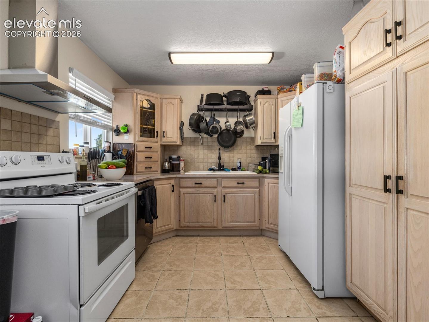 Kitchen featuring light wood-finish cabinetry, tile flooring, and a tile backsplash