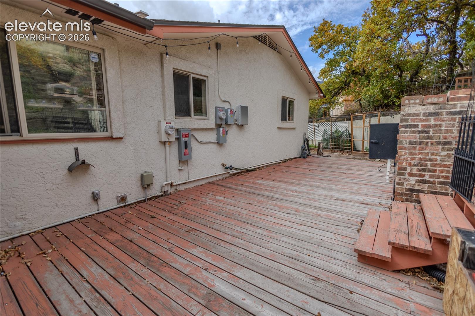 Exterior wood deck featuring a tiered staircase and brick retaining wall