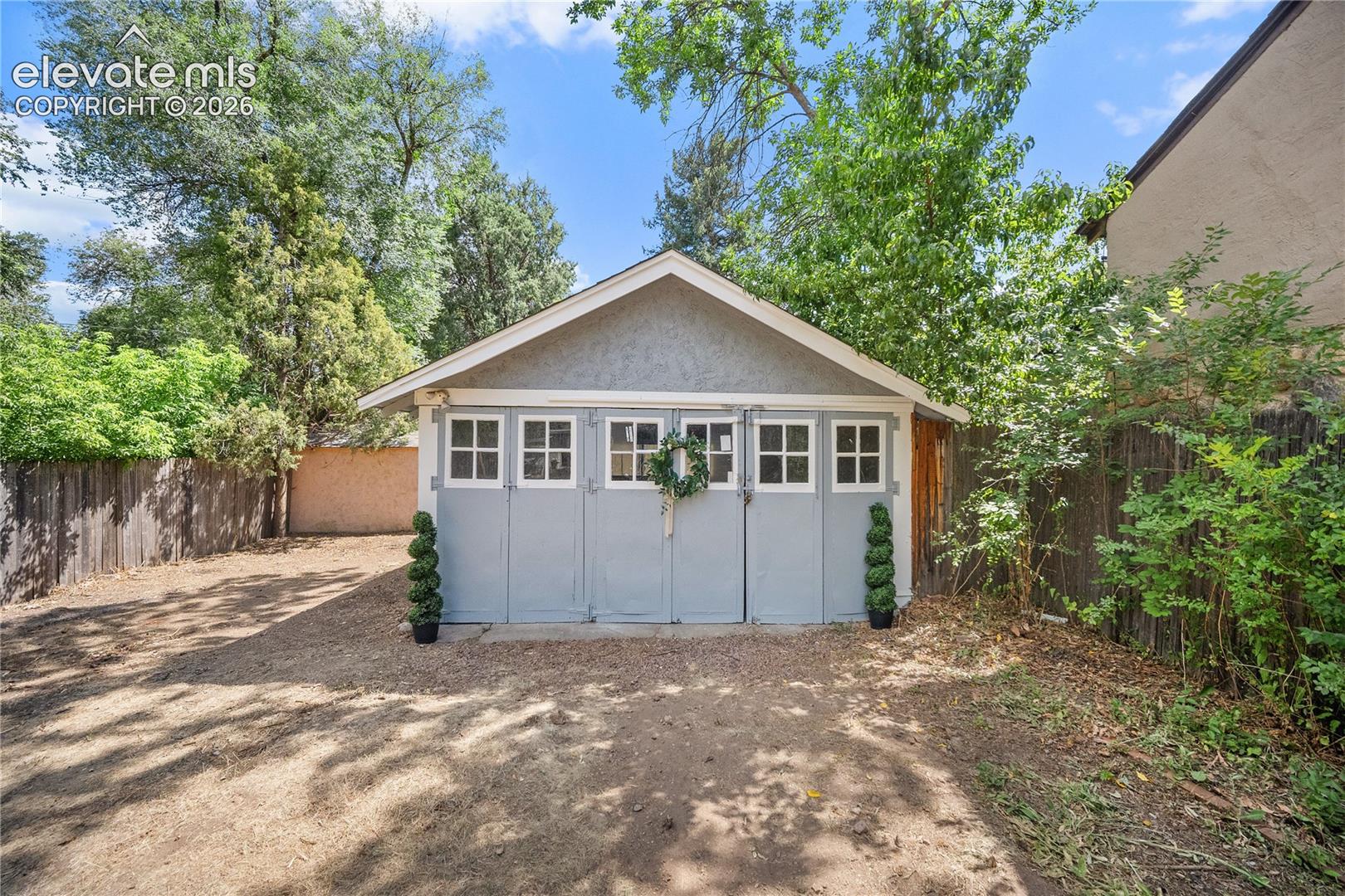 Detached garage with a gray stucco finish and a gabled roofline