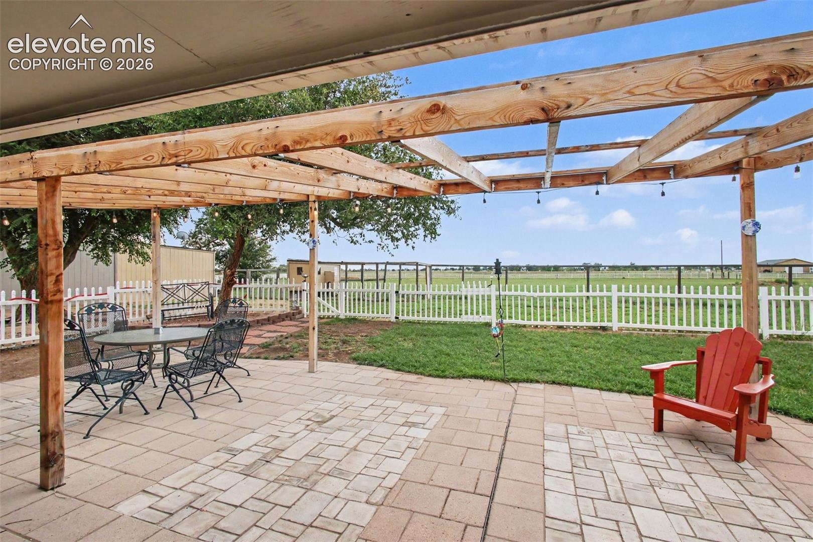 Beautiful outdoor retreat featuring a pergola with Edison lights, open space, and panoramic views—perfect for relaxing or entertaining.
