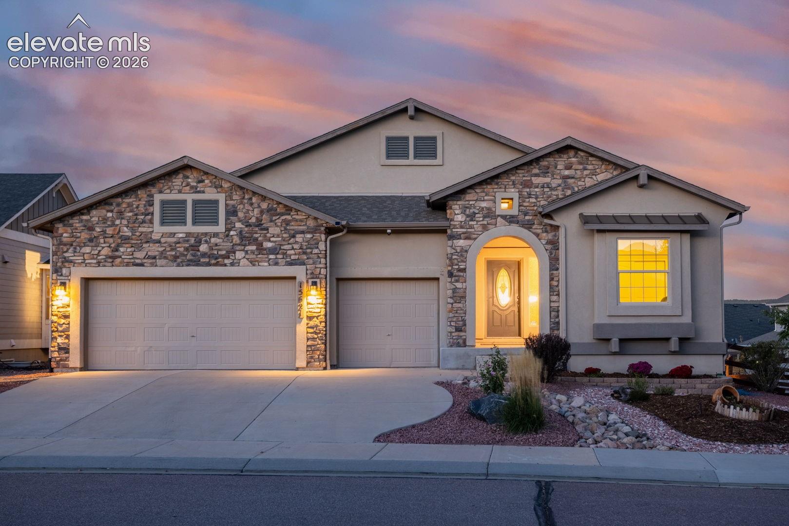 Ranch home in Forest Lakes, Monument, Colorado, featuring the Classic Homes Paradise floor plan, open-space views, and a finished garden-level basement. This thoughtfully designed home offers 5 bedrooms, 3 full bathrooms, and an attached 3-car garage with an electric vehicle charging station. The open-concept main level features a stone fireplace, inviting living and dining areas, and a spacious kitchen with an induction cooktop and a gas stub for a future range if desired. The main-level primary suite includes a generous walk-in closet and a 5-piece bathroom with dual vanities and a bathtub. A second main-level bedroom provides flexible space for a variety of uses. The finished garden-level basement includes three additional bedrooms, a full bathroom, and an additional living area. A composite deck overlooks open space, extending the living experience outdoors. Additional features include central air conditioning, a water softener, and an automatic sprinkler system. Forest Lakes community amenities include lake, walking and biking trails, parks, and open spaces. Bristlecone lake offers stand up paddle boarding, kayaking, catch and release fishing for residents only. Concert pavilion and a park. Convenient access to Monument shopping, dining, and I-25.