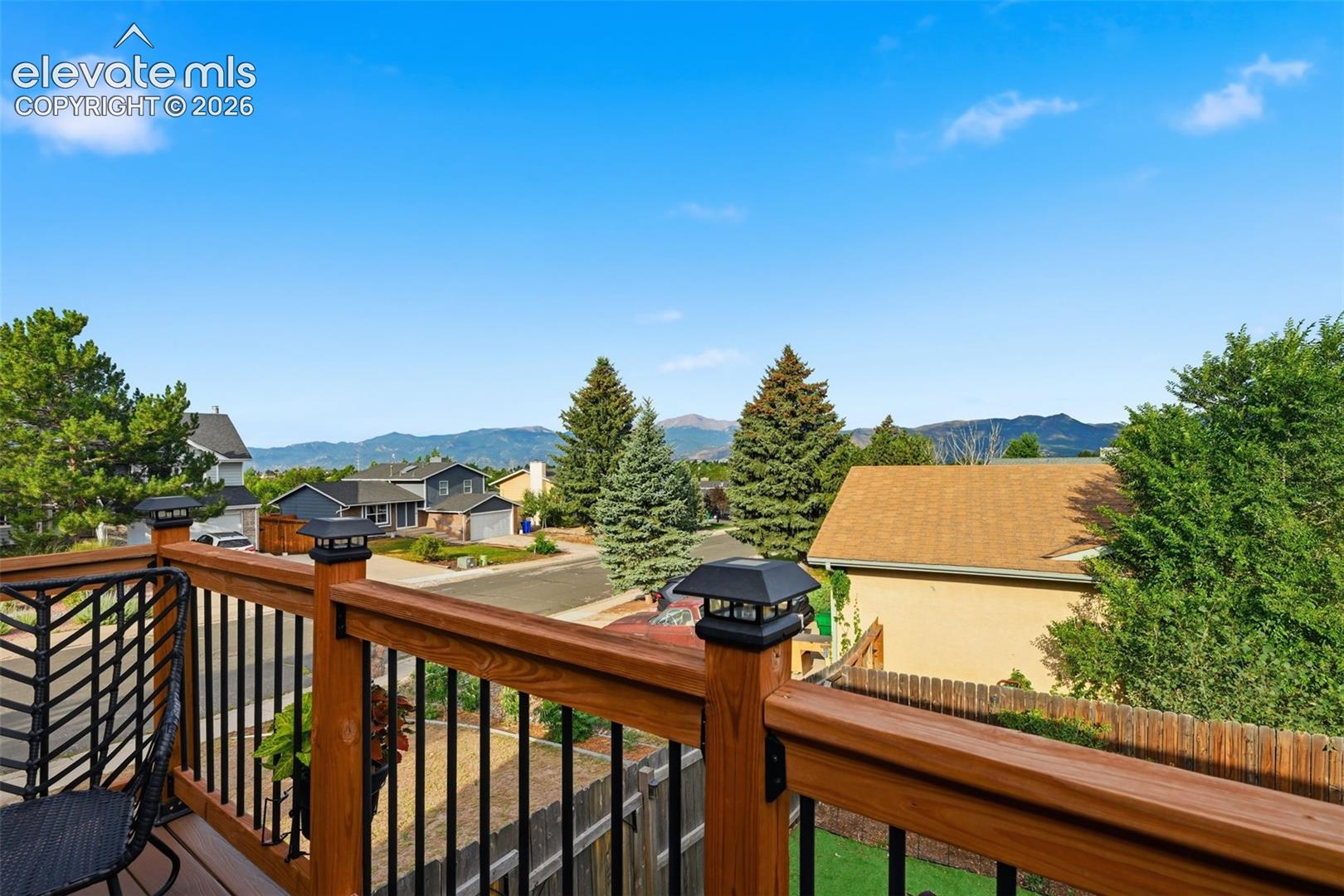 Expansive outdoor deck featuring wood newel posts, wood handrails, black metal balusters, and solar cap lights