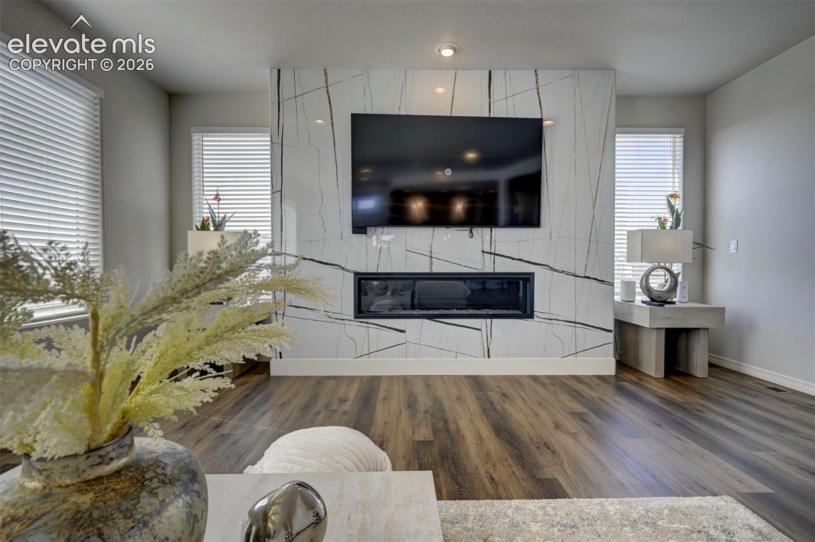 Feature wall with an integrated linear electric fireplace, recessed lighting, and wood-finish flooring throughout