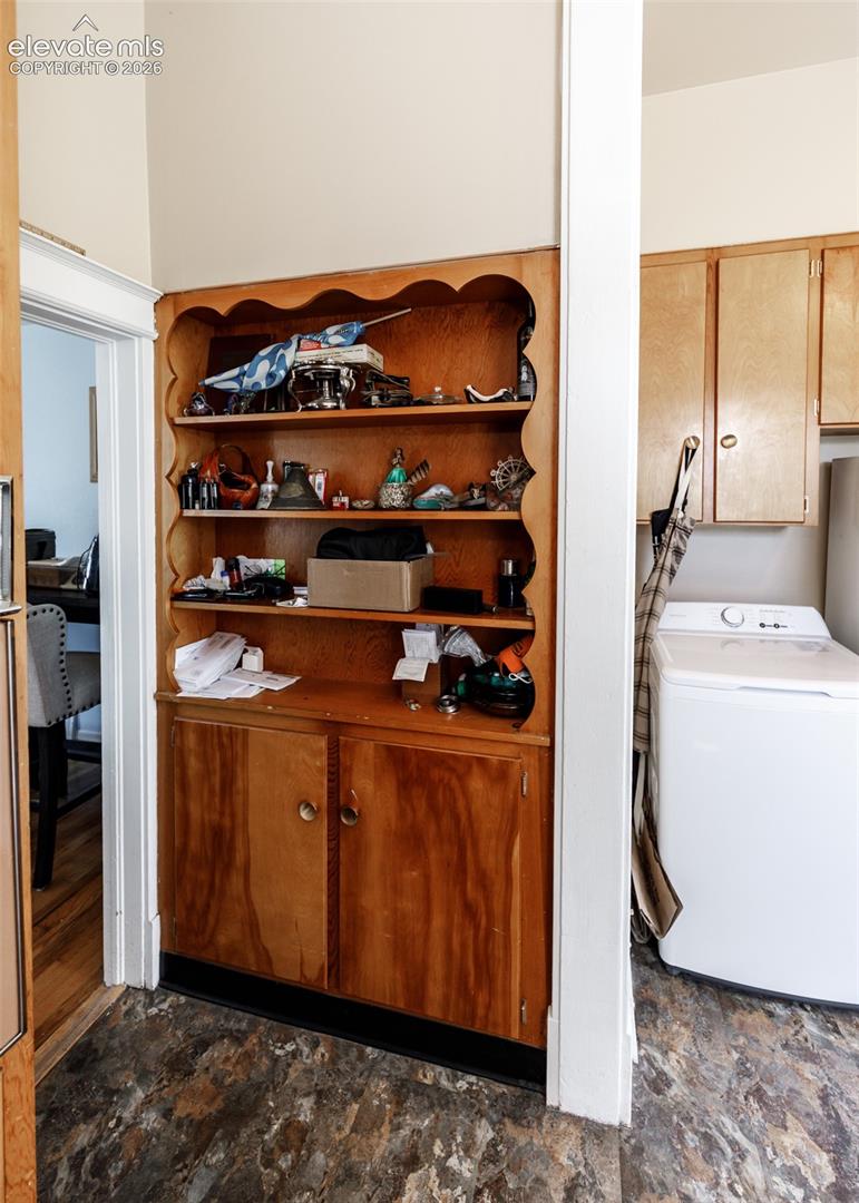 Built-in cabinetry with open shelving and lower storage, textured flooring, and a white appliance