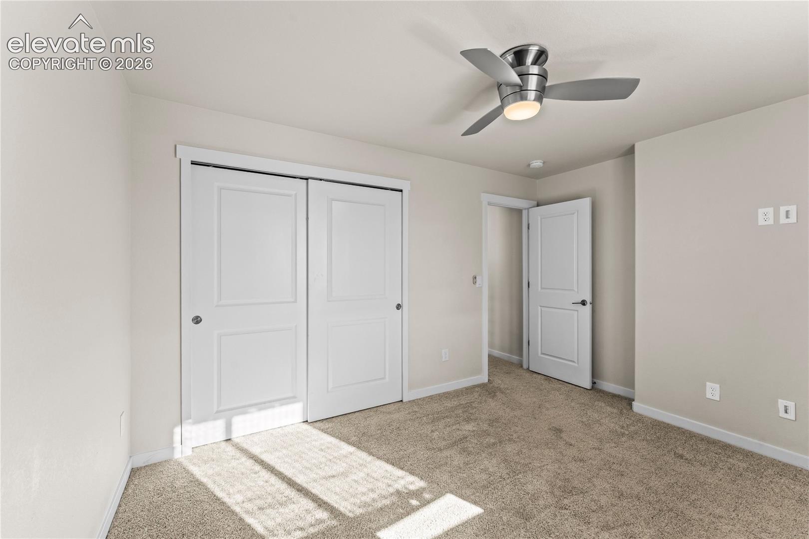 Neutral-toned walls, plush wall-to-wall carpeting, brushed nickel ceiling fan with integrated lighting, and multi-panel interior doors