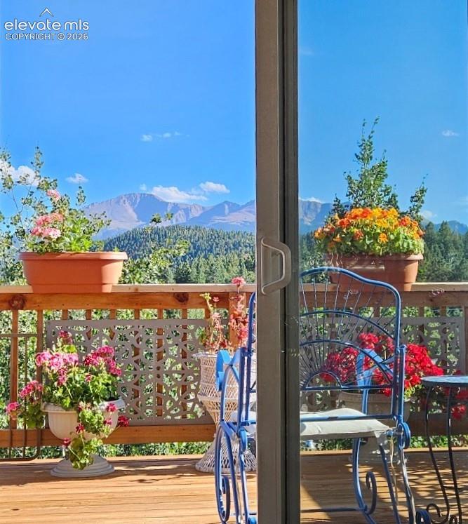 Sliding glass door leading to a wood-plank deck with a decorative railing and a distant mountain landscape