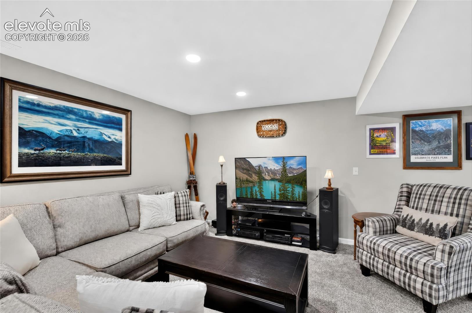 Recessed lighting illuminates a spacious room featuring wall-to-wall carpeting and a ceiling with a structural beam