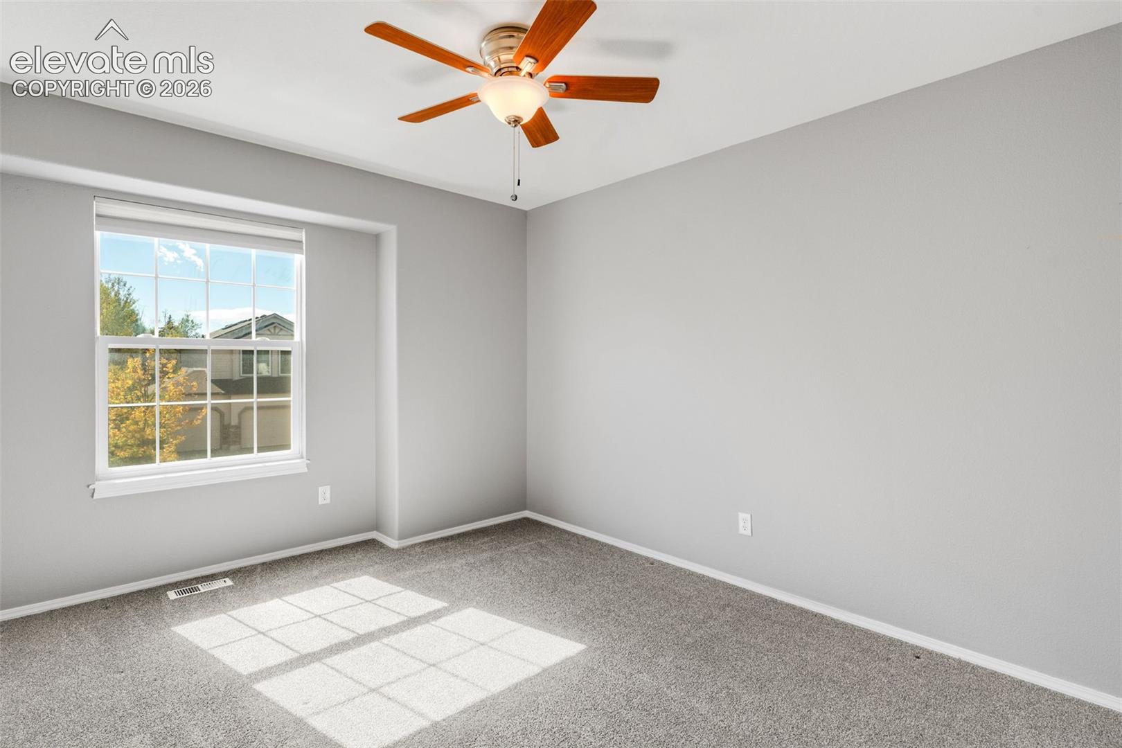Interior room featuring neutral wall paint, wall-to-wall carpeting, a multi-lite window with a recessed frame, and a central ceiling fan with integrated light fixture