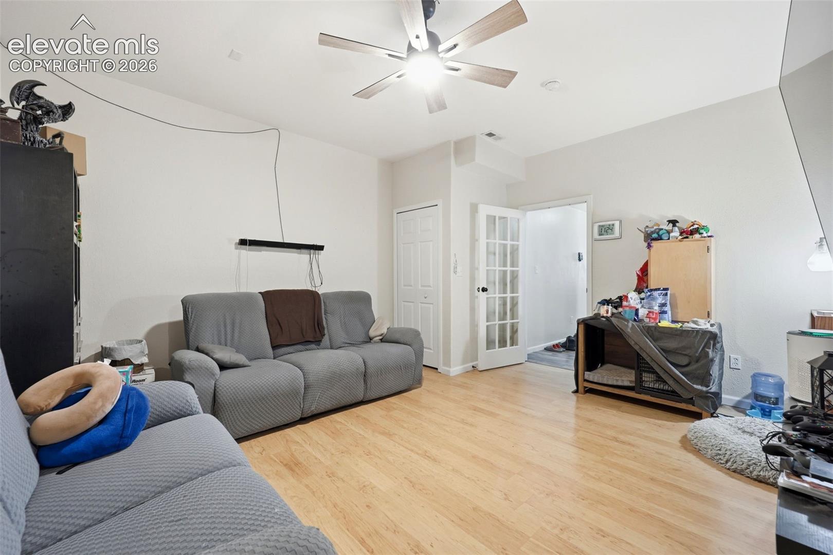 Living area featuring wood-finish flooring, light-colored walls, and a ceiling fan with integrated lighting