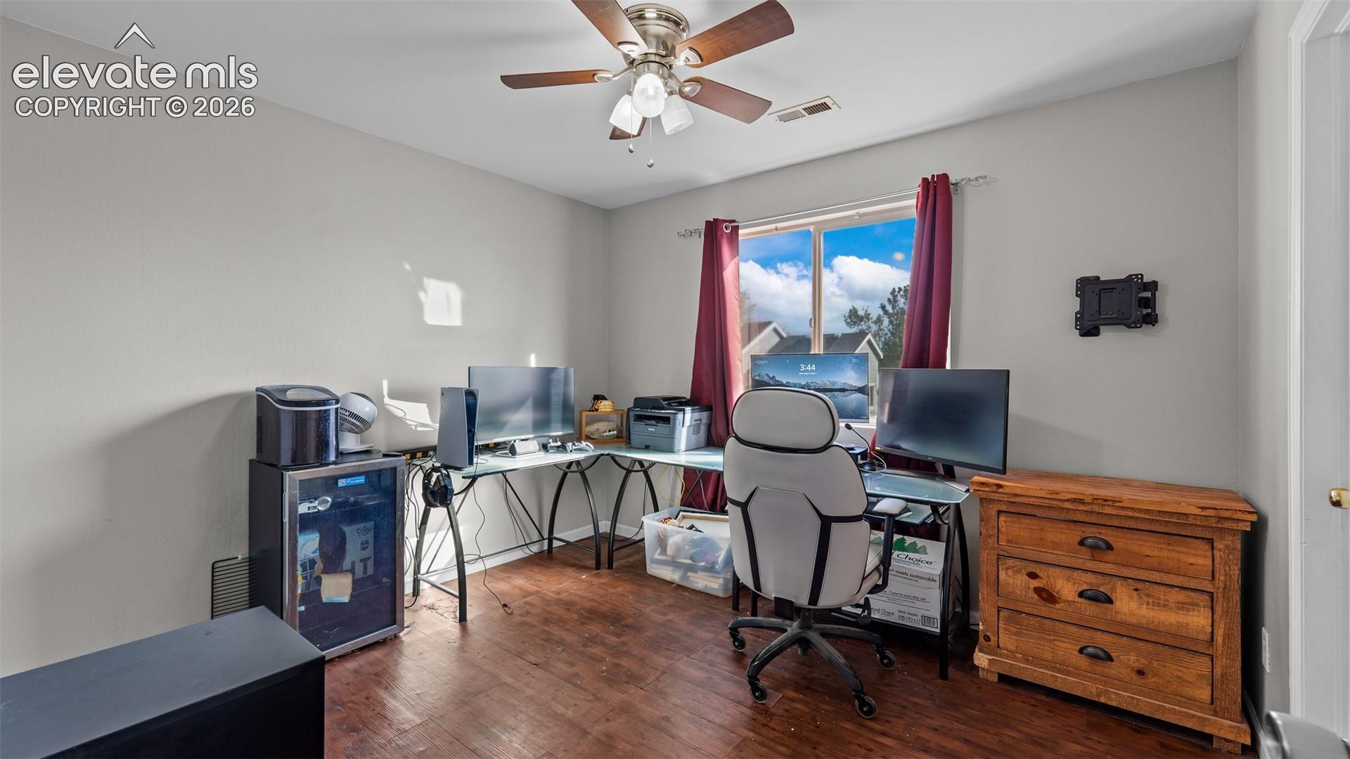 Wood-finish flooring, ceiling fan with integrated lighting, and a window providing natural light