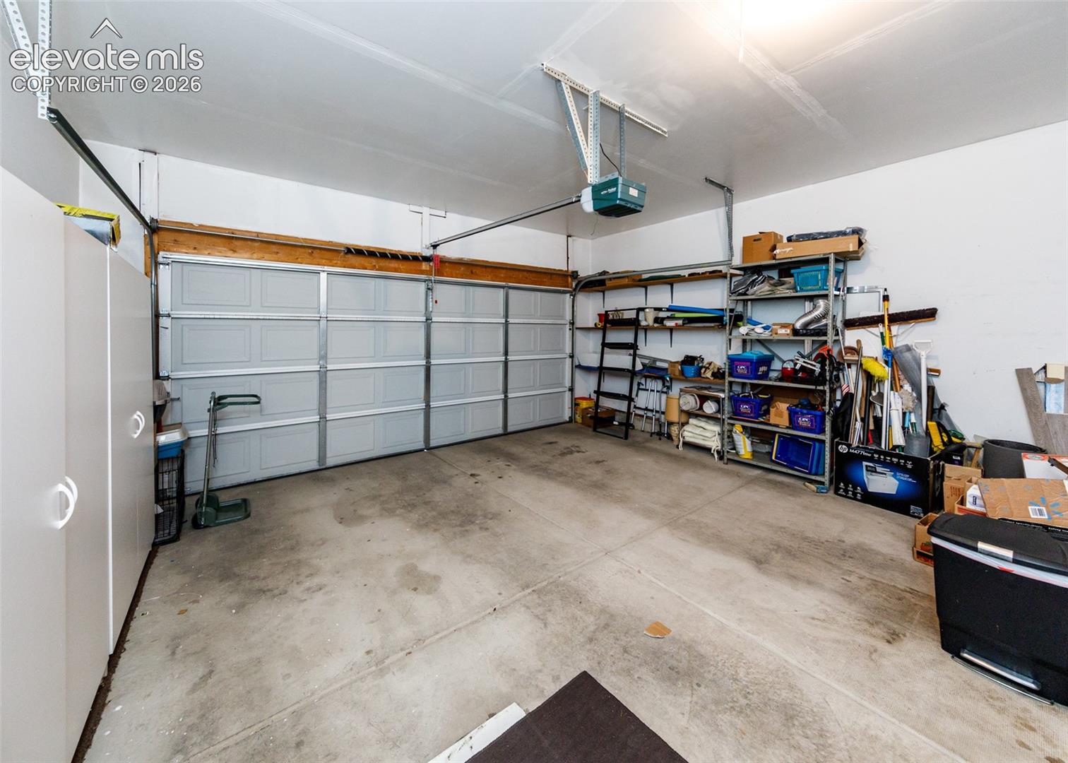 Two-car garage featuring a sectional overhead door, concrete flooring, and ceiling-mounted automatic door opener