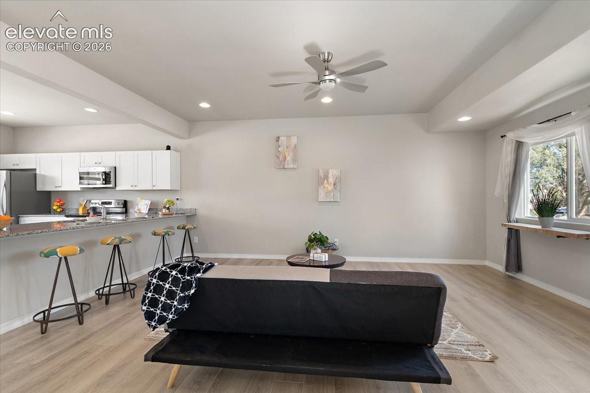 Open-concept living space with wood-finish flooring, recessed lighting, and a ceiling fan