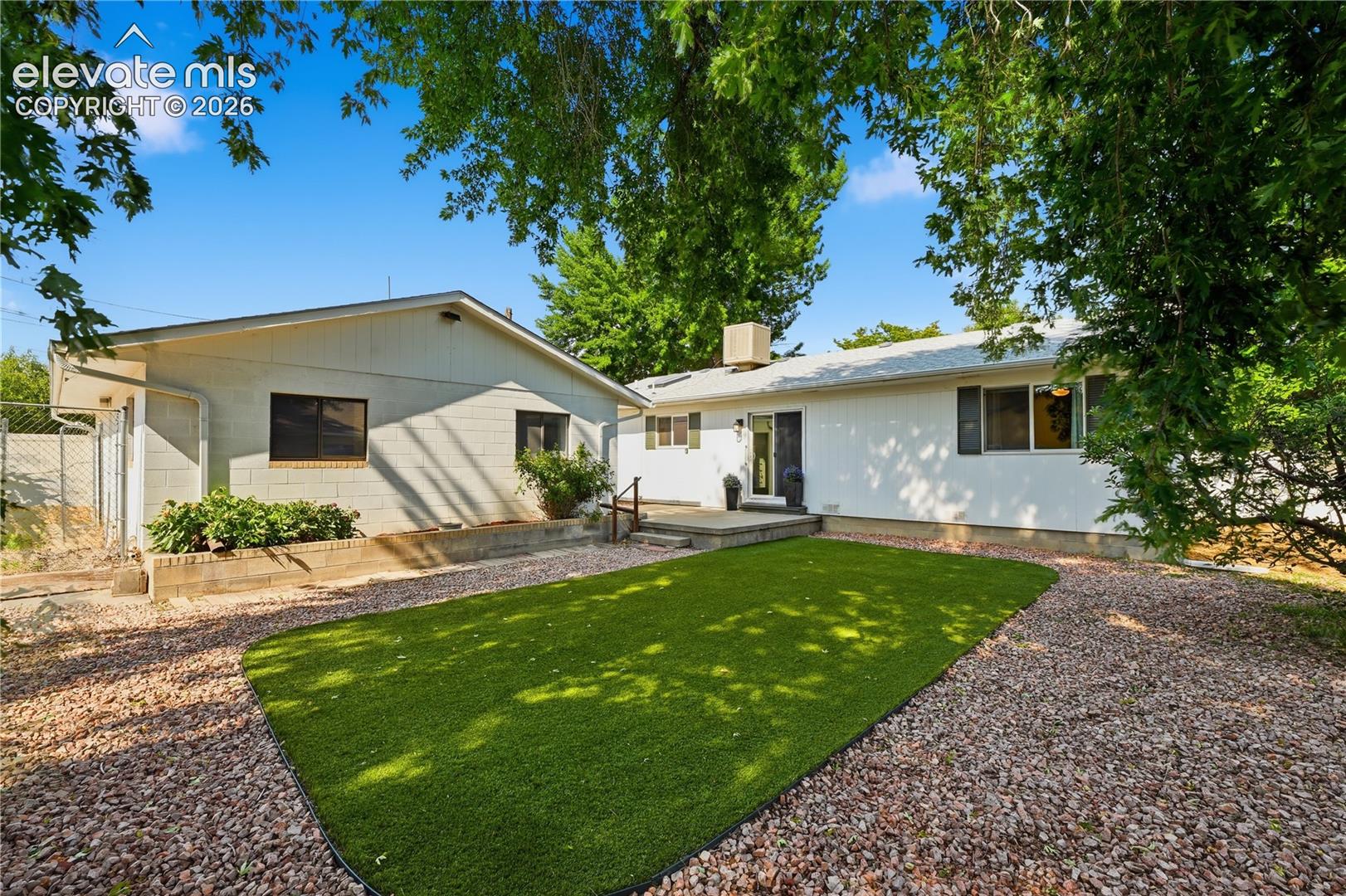 Private fenced backyard featuring low maintenance artificial turf, mature trees, and room to relax, entertain, or enjoy pets and play.