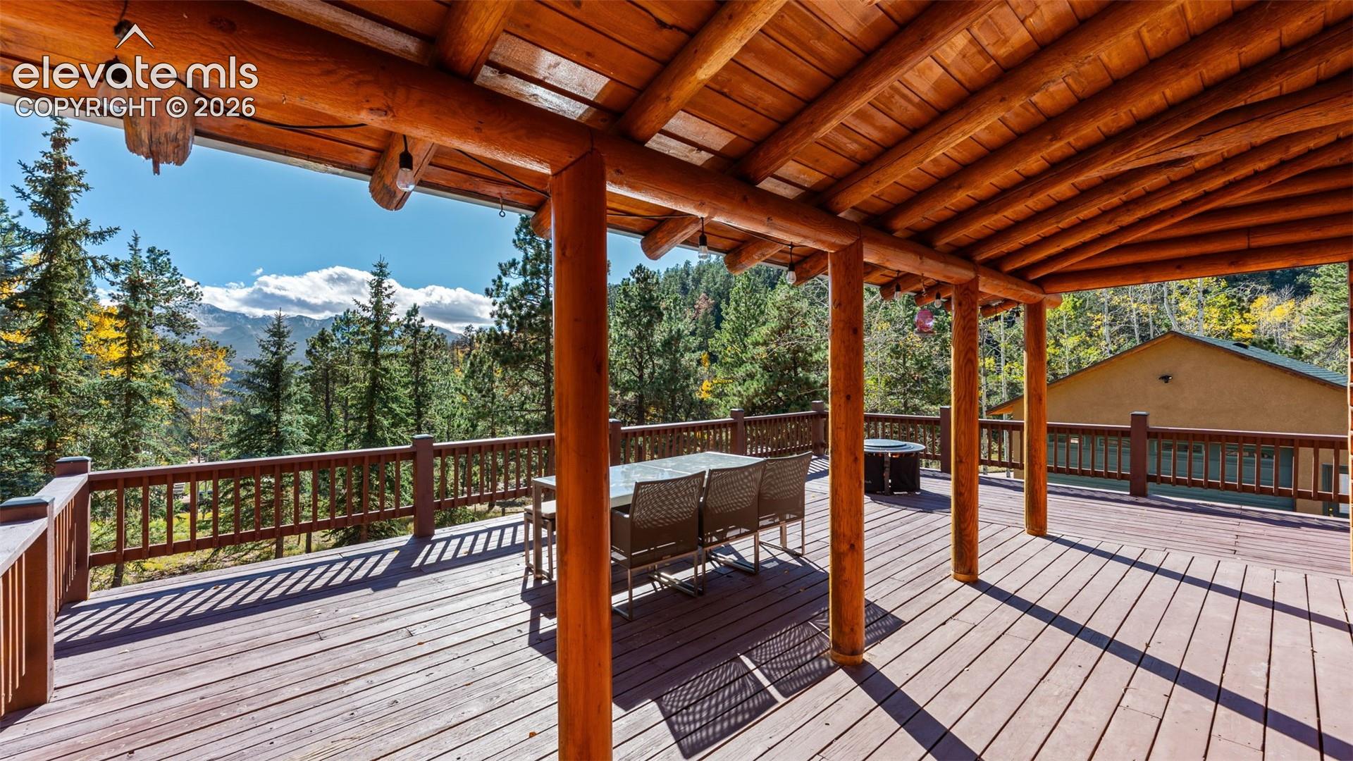 Expansive covered deck featuring timber-log support posts, exposed wood rafters, and natural wood decking with integrated railing