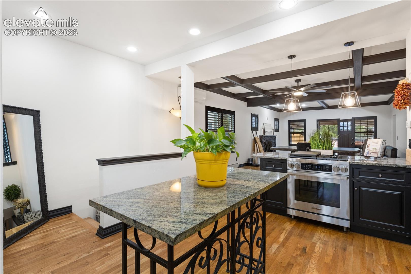 Kitchen featuring black cabinetry, granite countertops, stainless steel range, and wood-finish flooring
