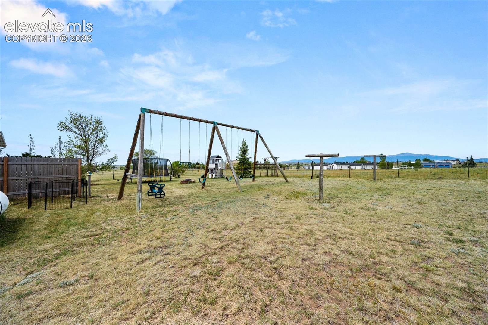 Expansive outdoor area featuring a swing set, additional play equipment, and a wooden privacy fence