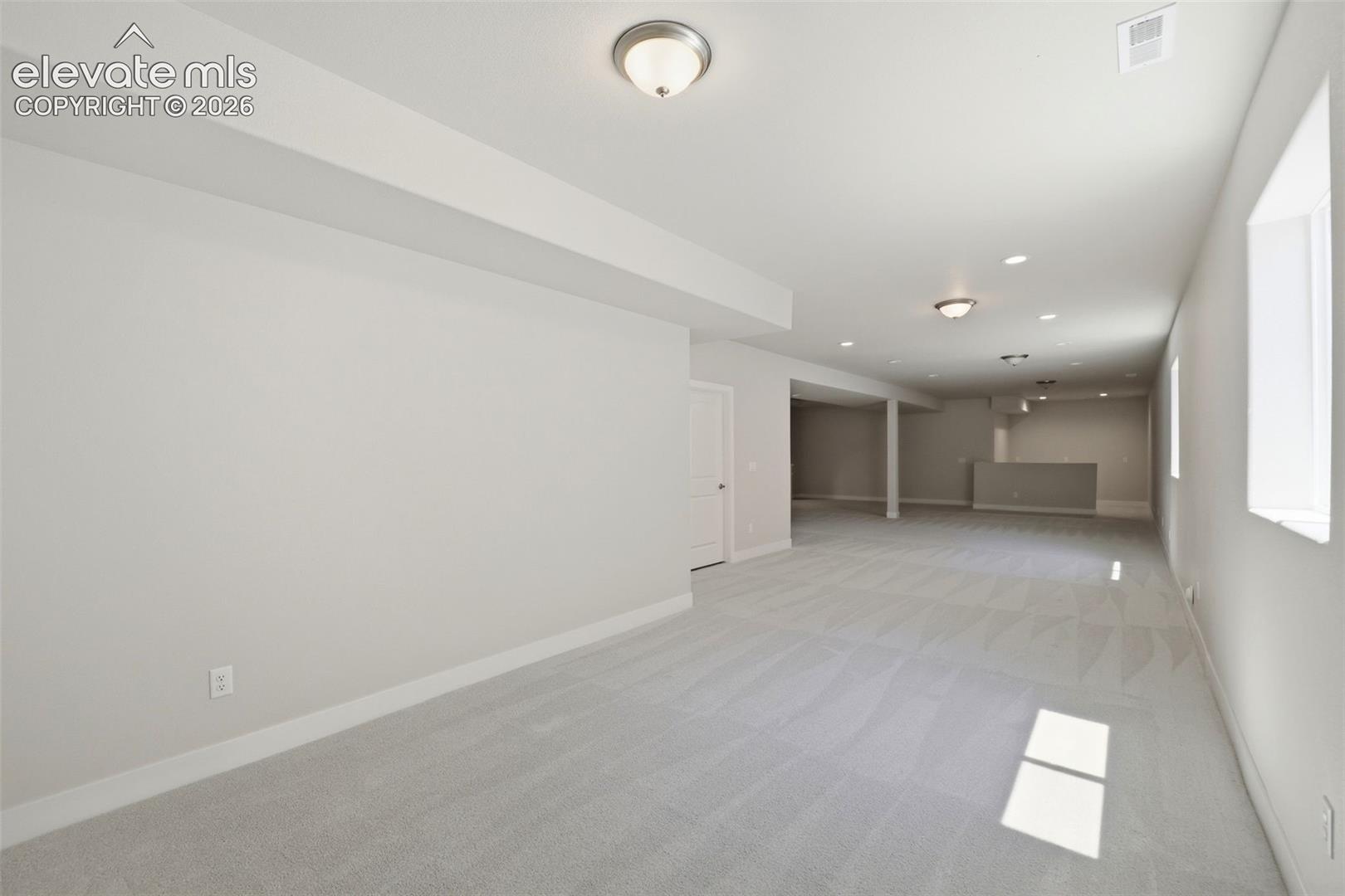 Neutral carpeted flooring, flush-mount ceiling lighting, recessed lighting, and multiple windows