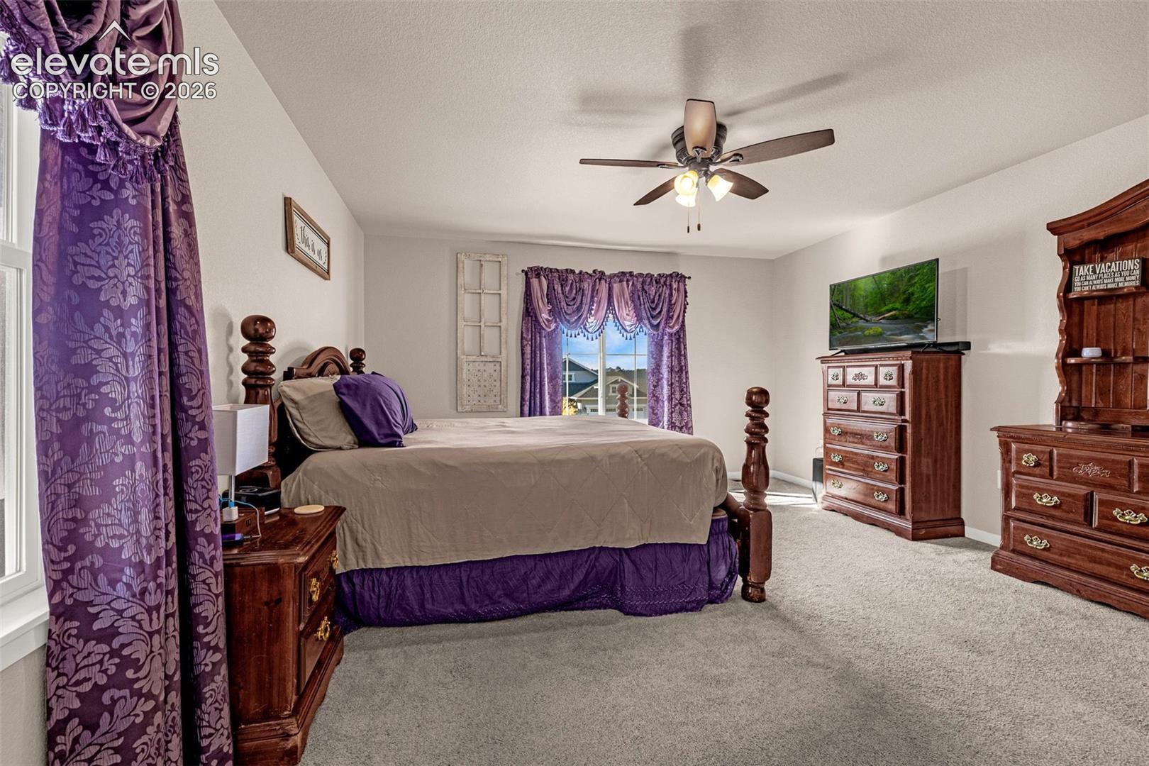Neutral carpeting, ceiling fan with integrated lighting, and window with natural light