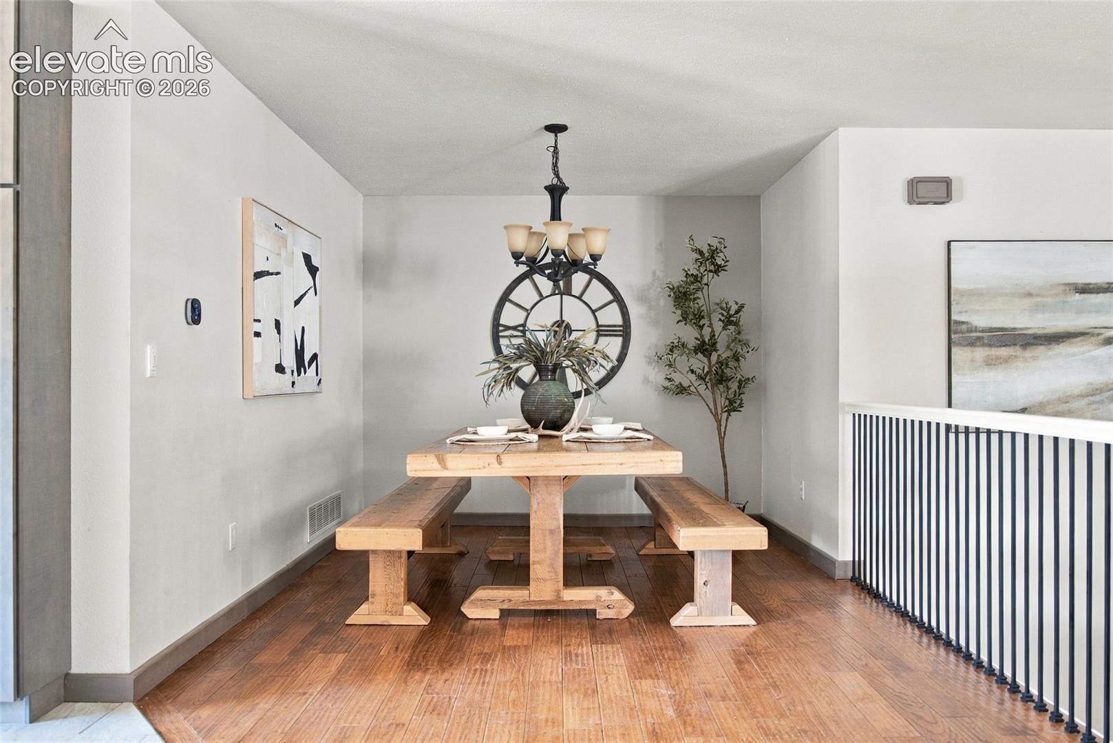 Wood-finish flooring with a modern chandelier and a metal spindle railing
