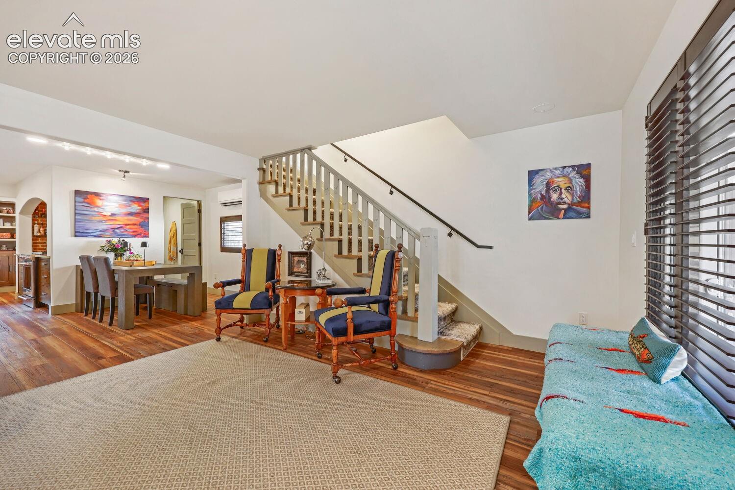 Hardwood flooring throughout the main level, staircase with wood banister, built-in shelving, and recessed lighting