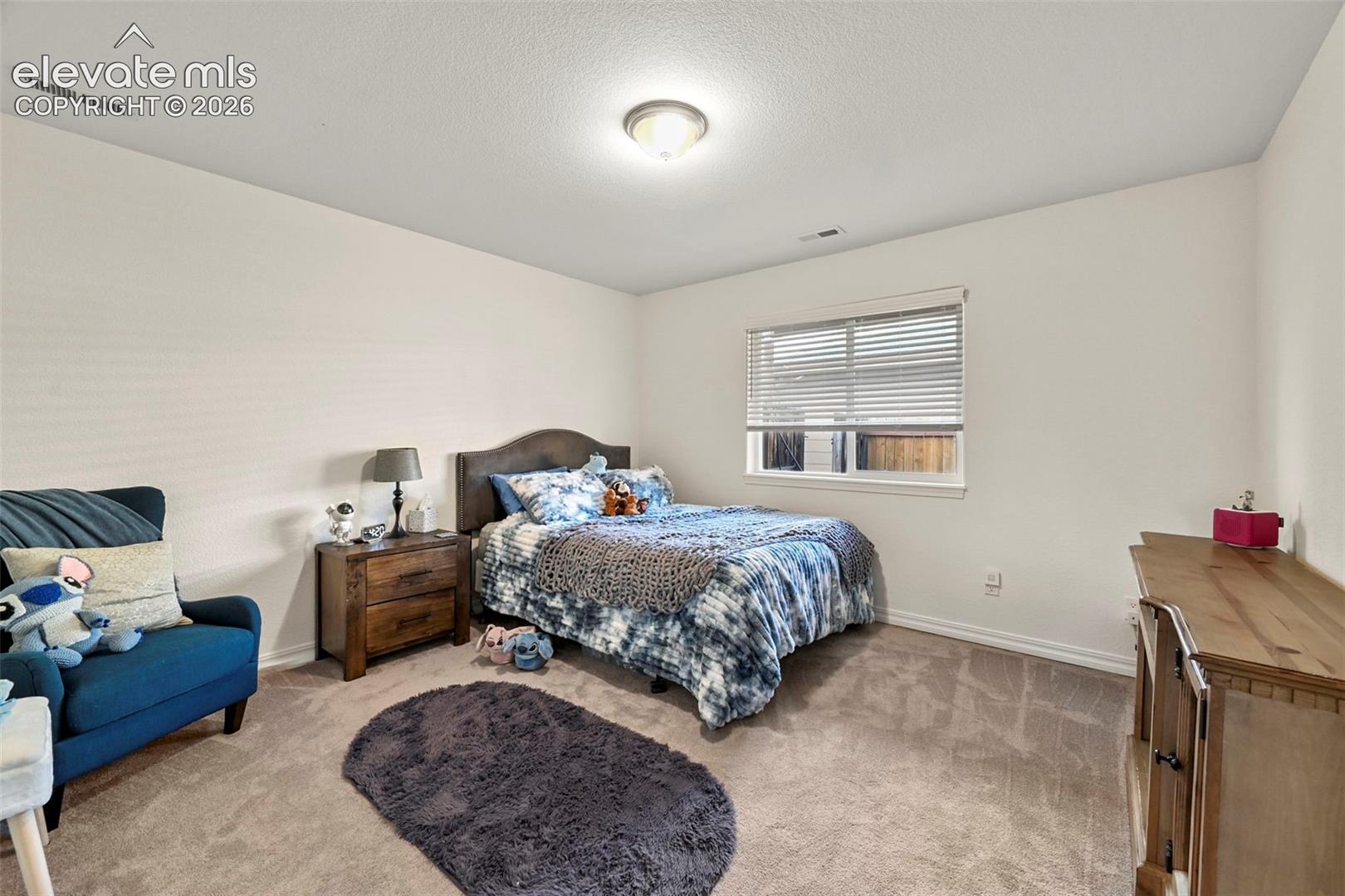 Neutral-toned carpeting, white walls, and a window with blinds