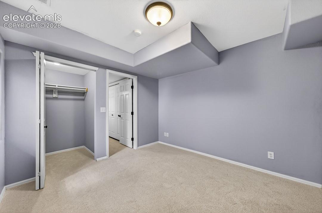 Interior room featuring neutral-toned wall paint, neutral carpeting, a built-in closet with shelving, and a semi-flush mount ceiling light fixture