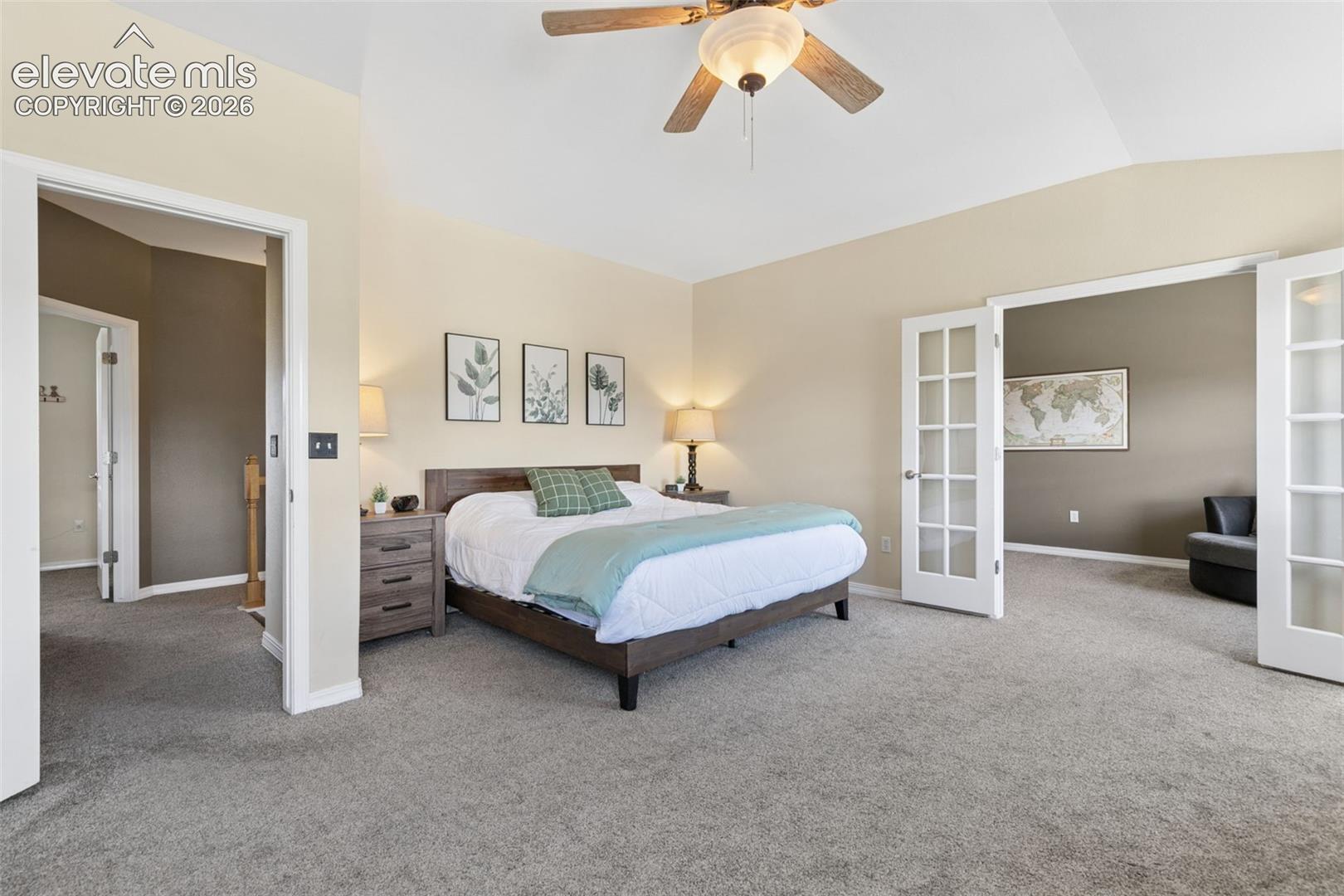 Vaulted ceiling with a ceiling fan, plush gray carpeting, and double French doors with clear glass panels