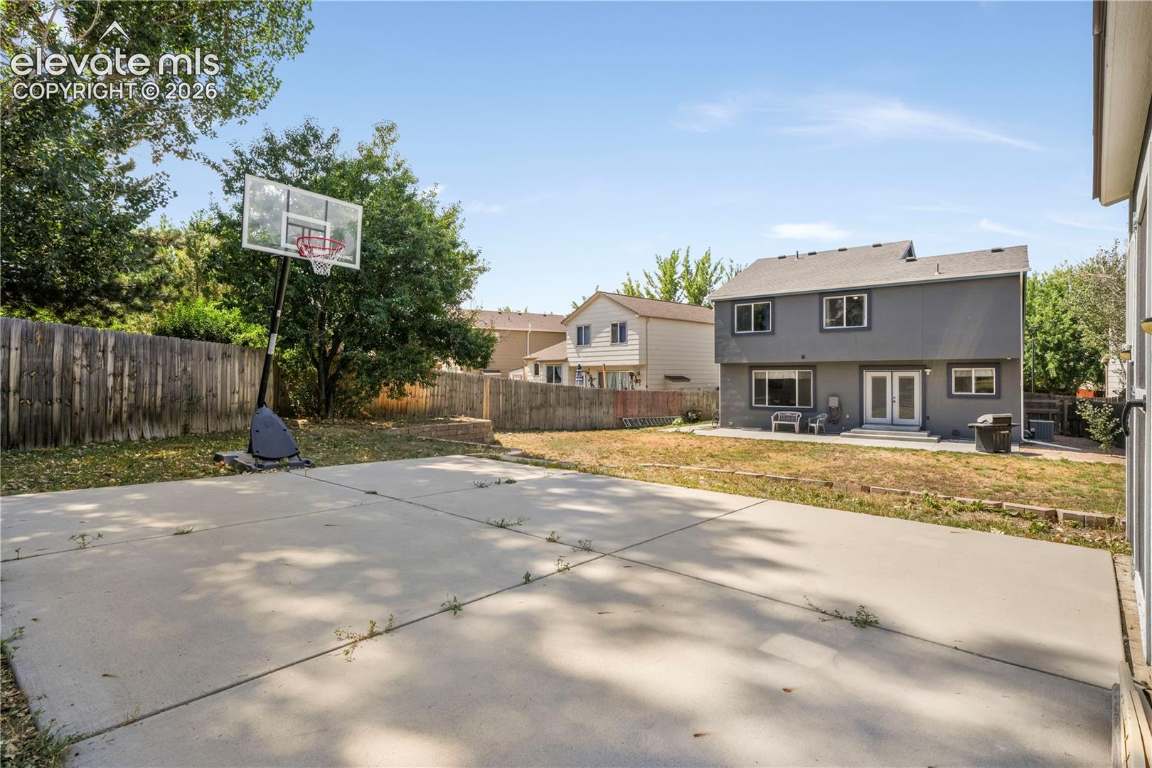 Back of home with large backyard patio, multiple levels, basketball goal and shed for storage