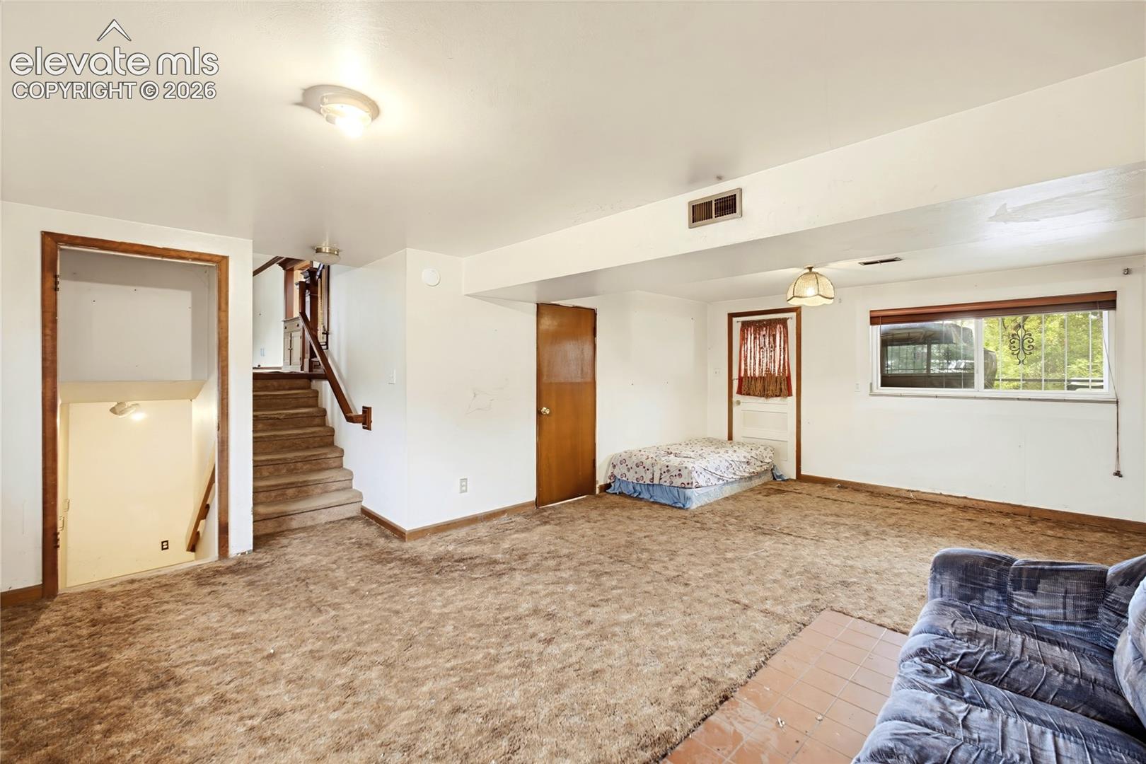 Carpeted room featuring a window, overhead lighting, and interior doorways