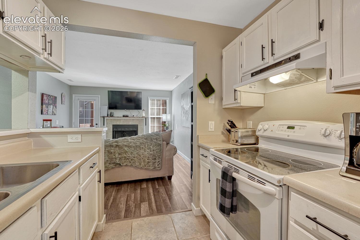 Kitchen featuring white cabinetry, light-toned countertops, a built-in range, and a stainless steel sink