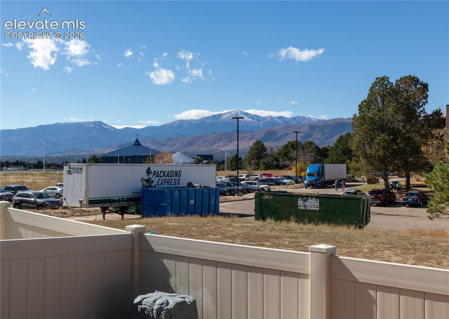 Mountain backdrop featuring prominent snow-capped peaks and vinyl privacy fencing