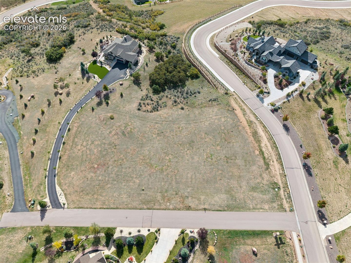 Expansive corner lot featuring paved street access, native vegetation, and established surrounding residential infrastructure