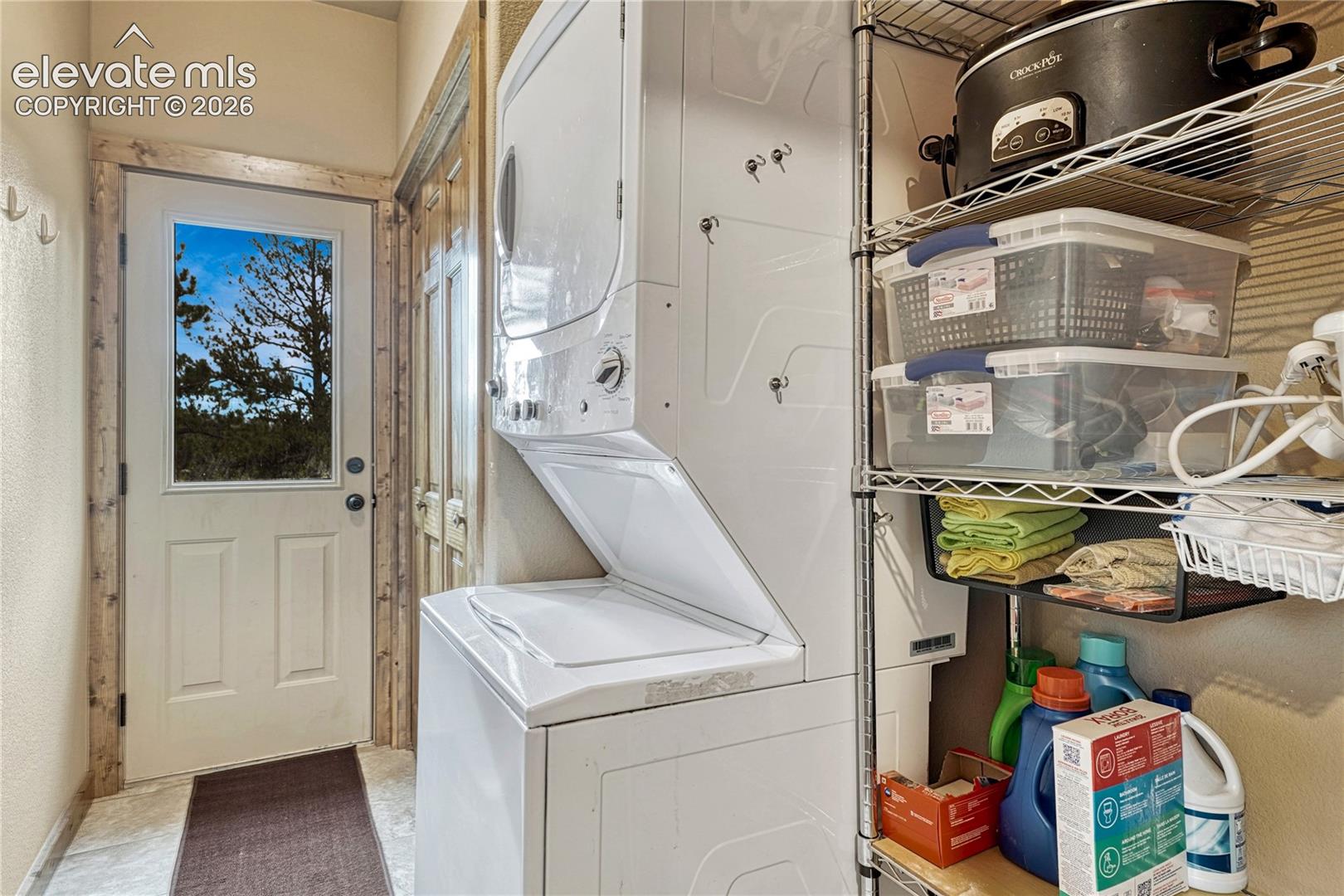Stacked washer and dryer unit, exterior door with glass insert, and natural wood-trim door casing