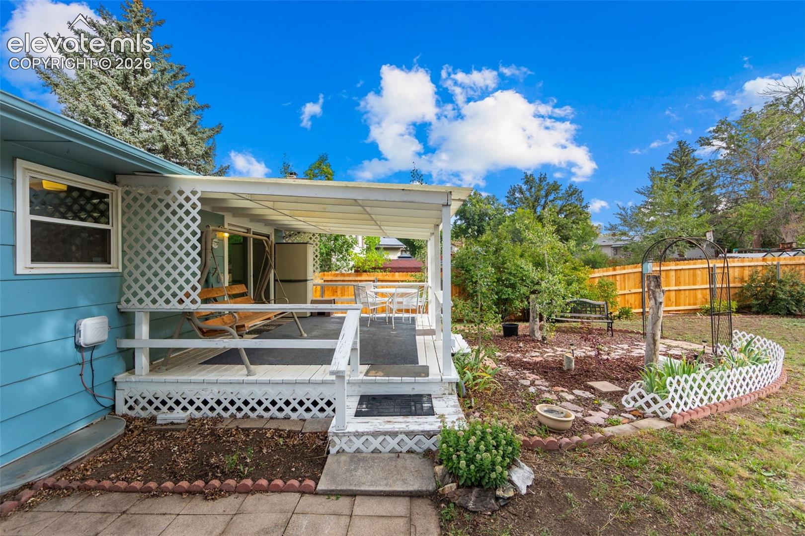 Covered deck with white lattice railing, wood deck surface, and direct yard access