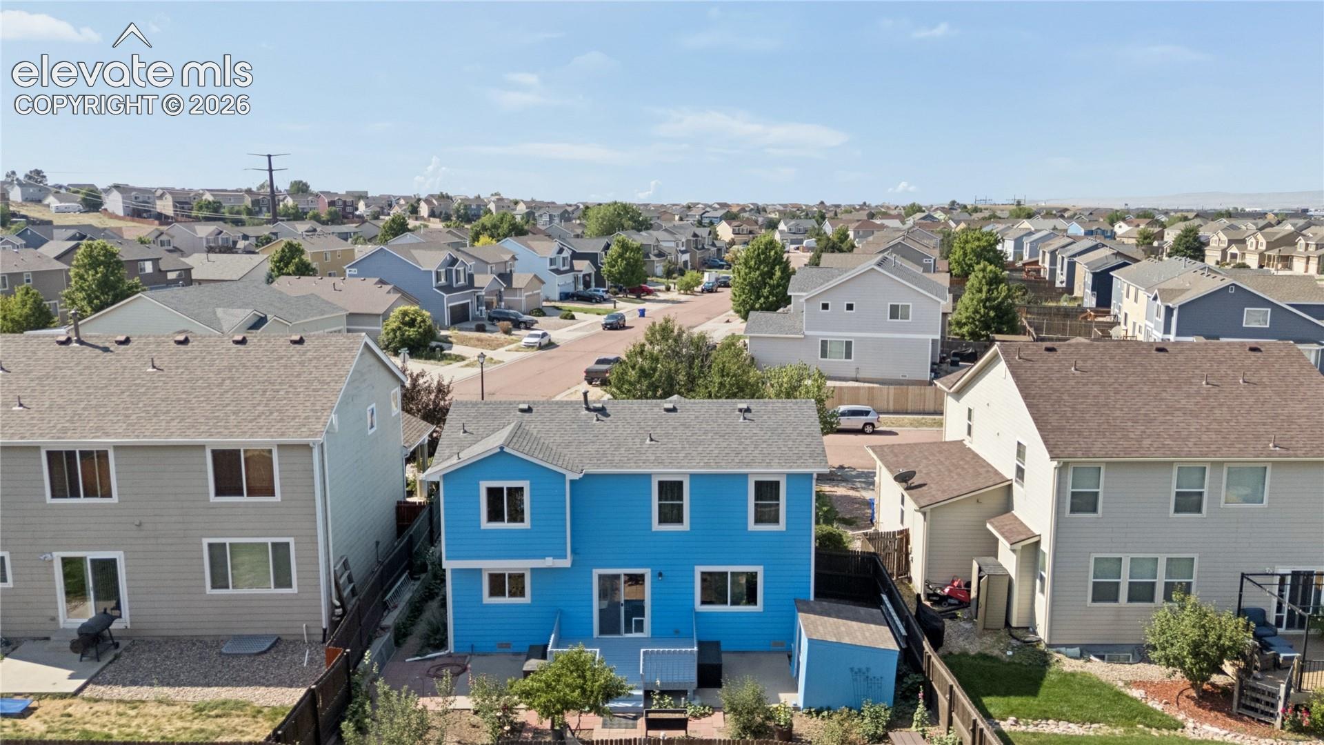Blue two-story residence with a patio, fenced yard, and an exterior shed