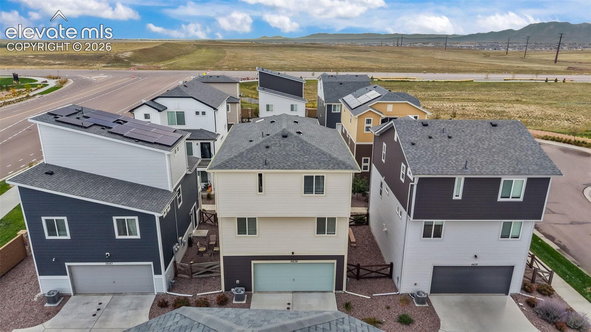 Multi-level residential structures featuring mixed-material siding, asphalt shingle roofing, attached multi-car garages, and rooftop solar panel arrays