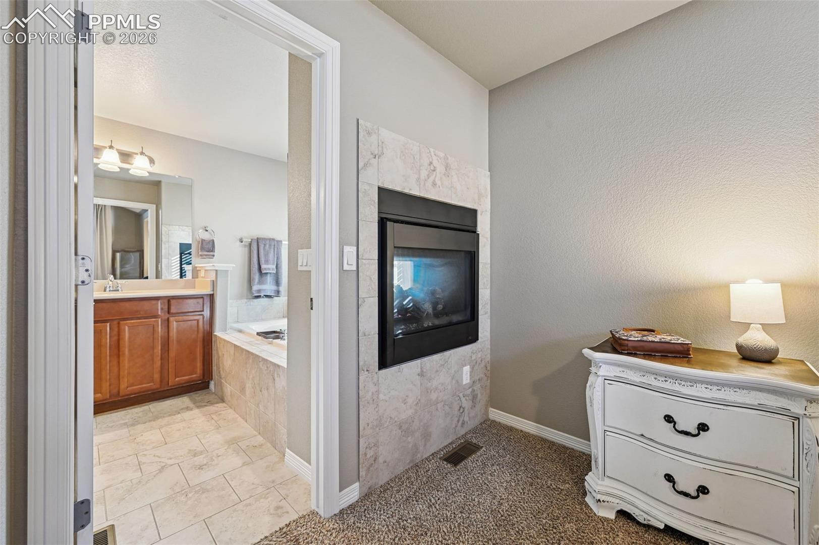 Bathroom with vanity, a garden tub, light carpet, and a premium fireplace