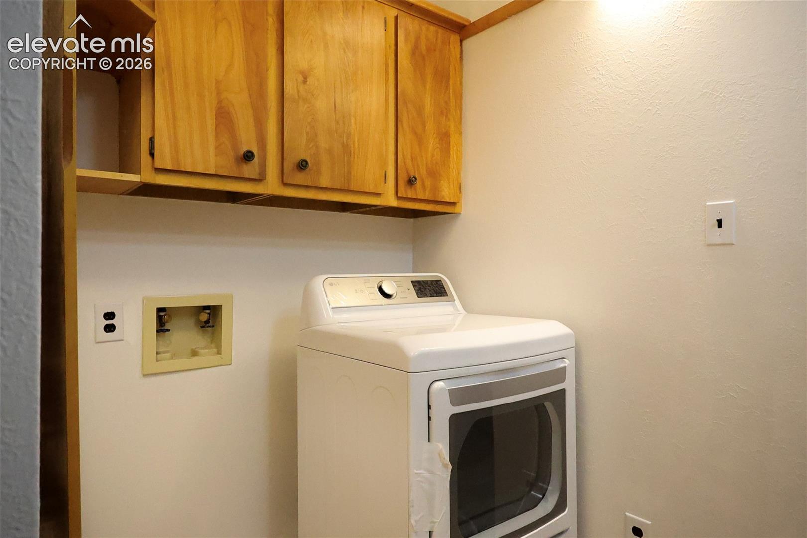 Laundry area with wood cabinetry and an appliance hookup