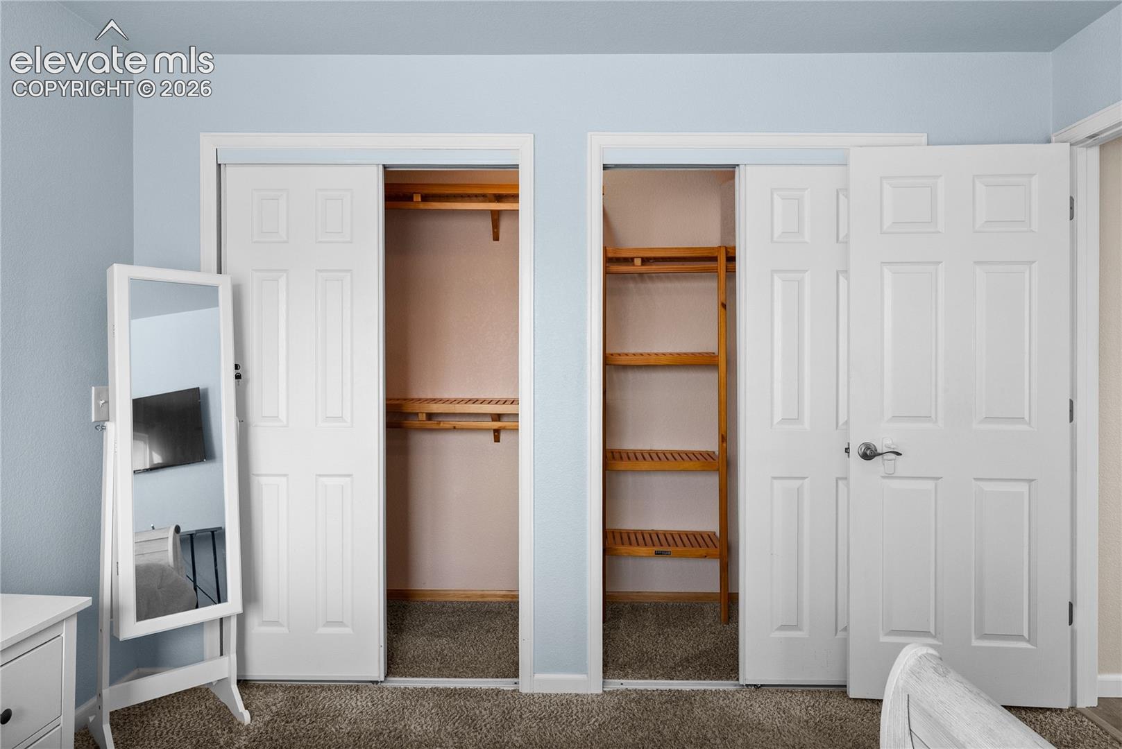 Dual closets featuring paneled sliding doors and interior wood shelving