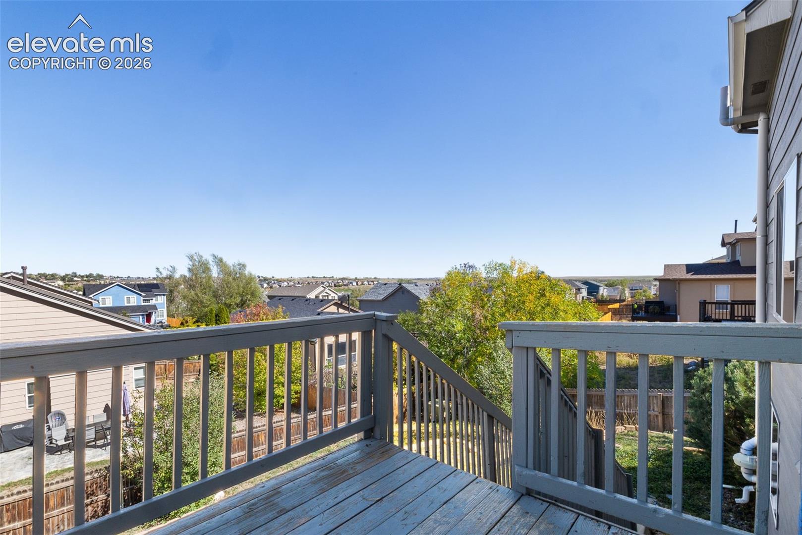 Raised wood-plank deck featuring a painted balustrade, integrated stairs, and an expansive exterior outlook