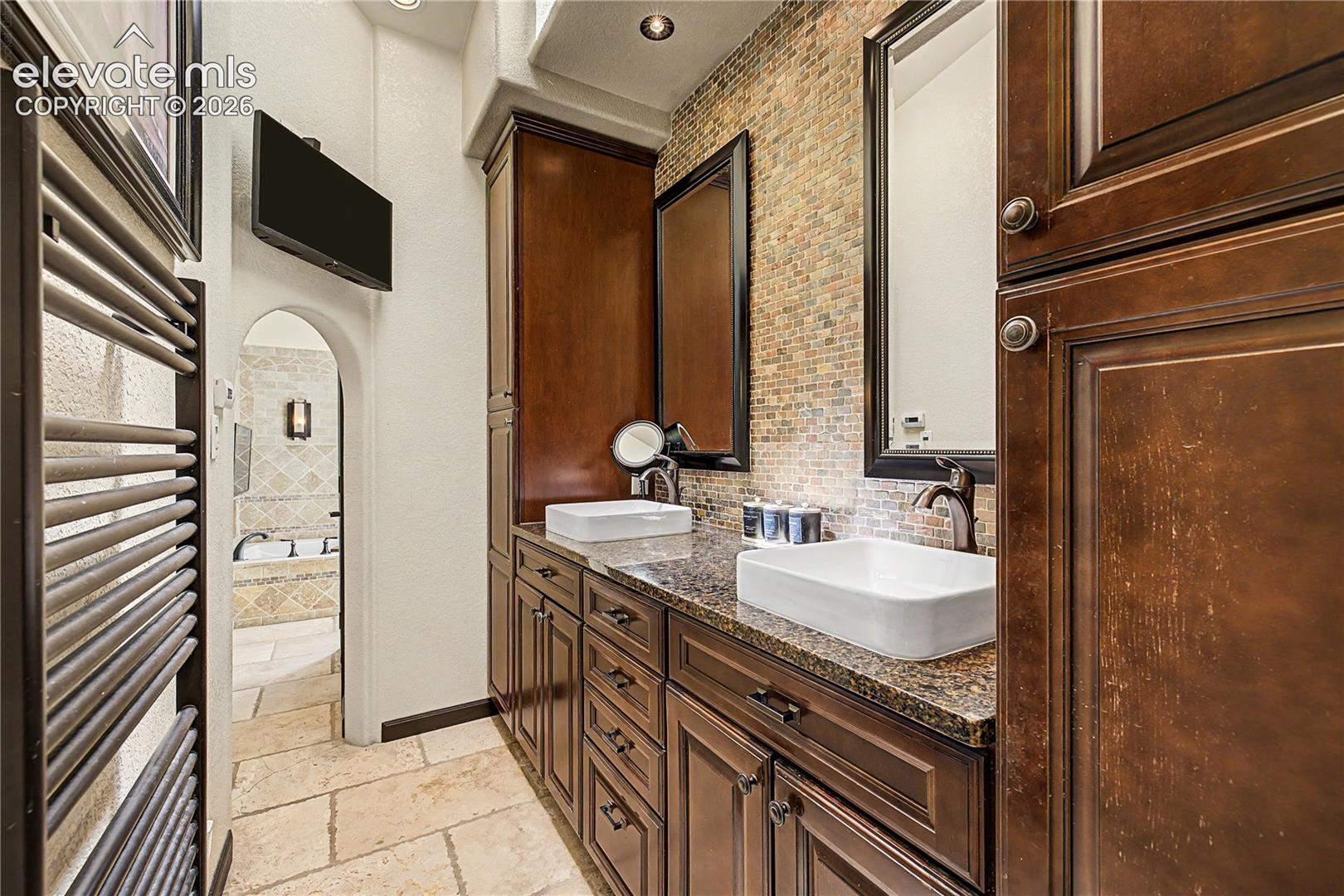 The primary bath's stacked-stone accent wall and rich wood vanity elevate everyday routines into something closer to a spa experience.