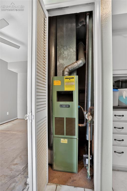 Utility closet featuring a residential furnace unit with exposed ductwork and louvered bifold doors