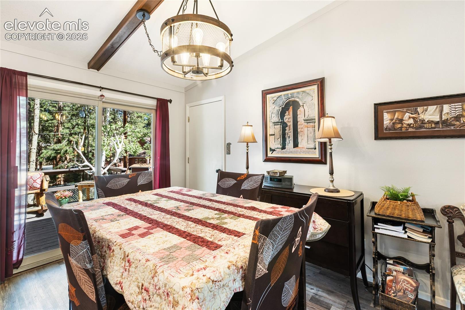 Vaulted ceiling with an exposed wood beam, modern chandelier, sliding glass doors, and wood-finish flooring